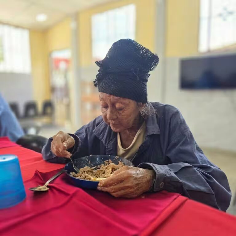 Persona mayor recibiendo alimento en comunidad